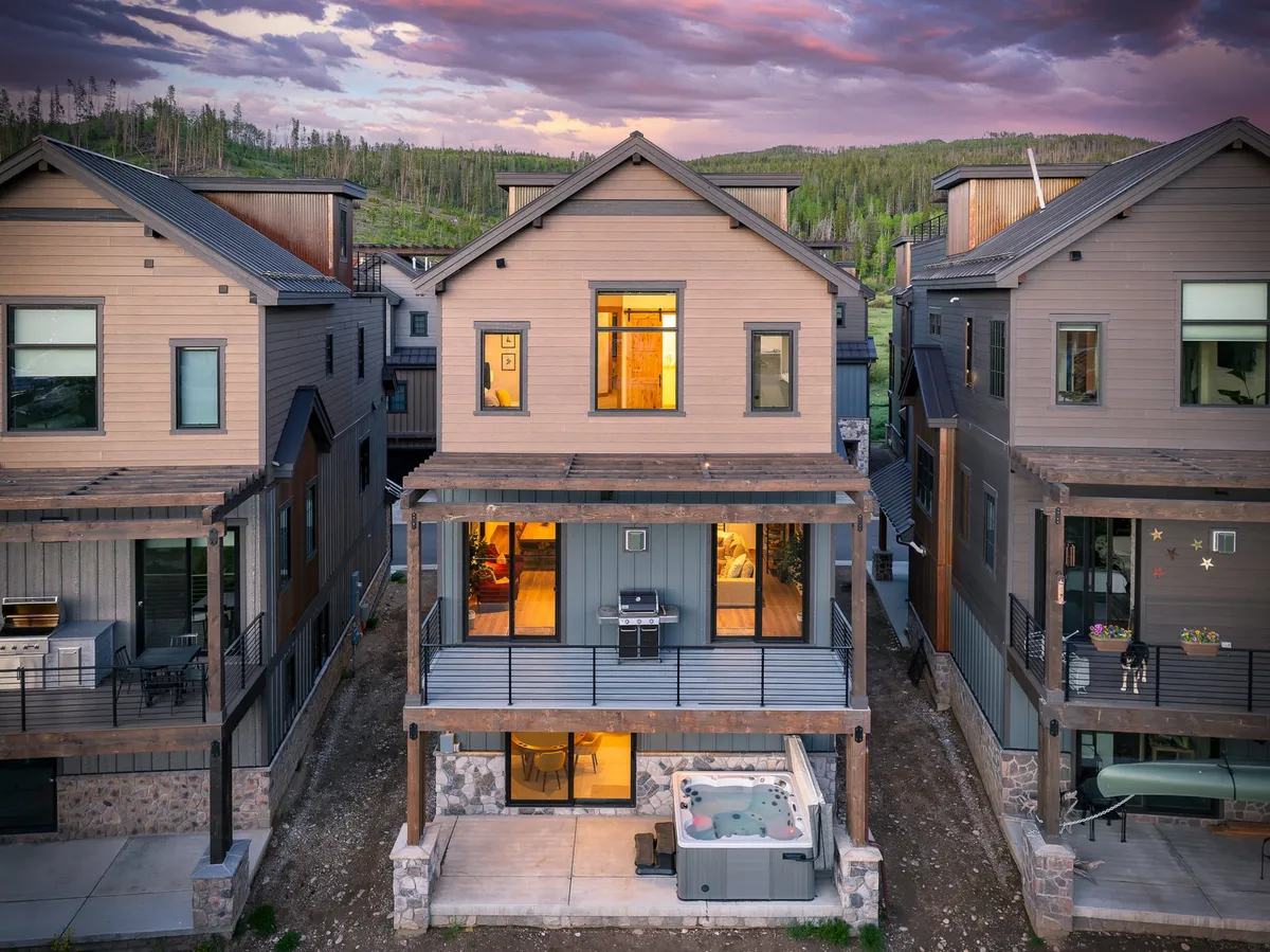 A welcoming exterior shot featuring the villa’s front porch, a hot tub, and large windows, with an outdoor grill positioned nearby. The scene suggests a space perfect for group relaxation, outdoor dining, and evening gatherings.
