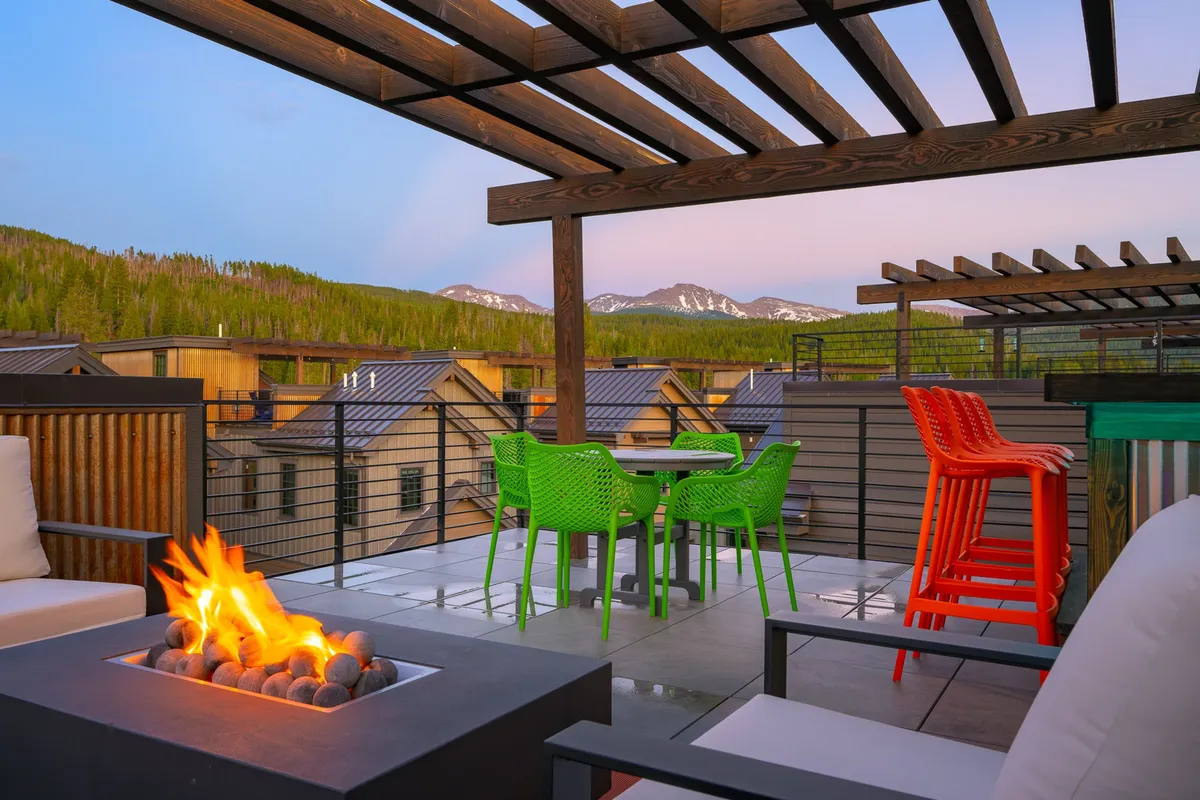 An outdoor area with a fire pit surrounded by colorful chairs, set against a backdrop of mountain views. The scene is vibrant and cozy, ideal for social gatherings, evening relaxation, and creating family memories under the stars.
